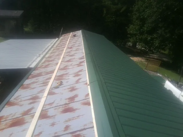Old rusted panels beside newly installed green metal roofing — Wind Damage Roof Repair by Roofing Brothers in Reed