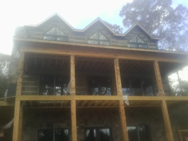 Dormers and porch framing on a large log home under construction — Roof Coating work by our crew in Reed