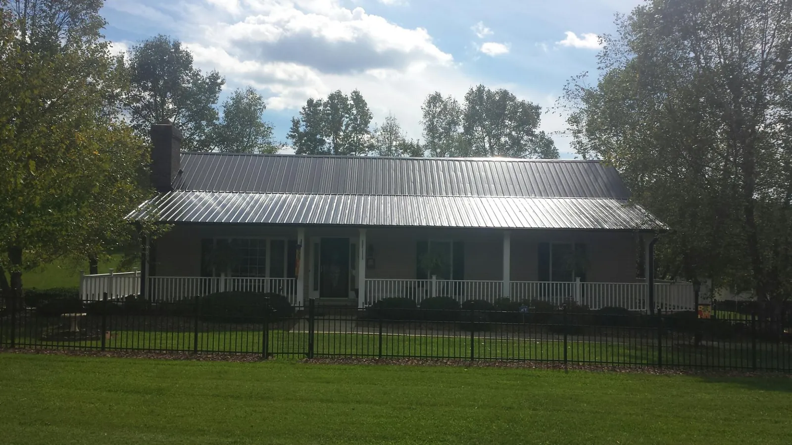 Gray metal roof on a brick ranch with a full width front porch — Gutter Guard Installation work by our crew in Reed
