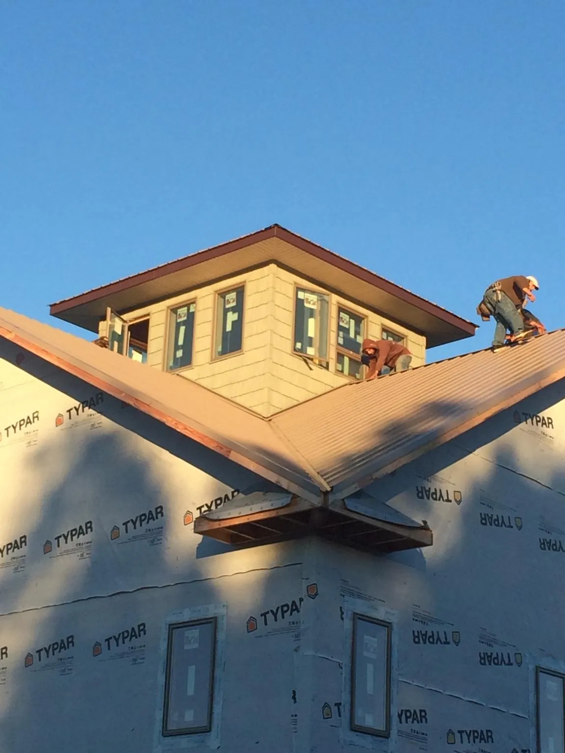 Roofers working around a rooftop cupola on a new metal roof at sunset — Roof Waterproofing in Reed by Roofing Brothers